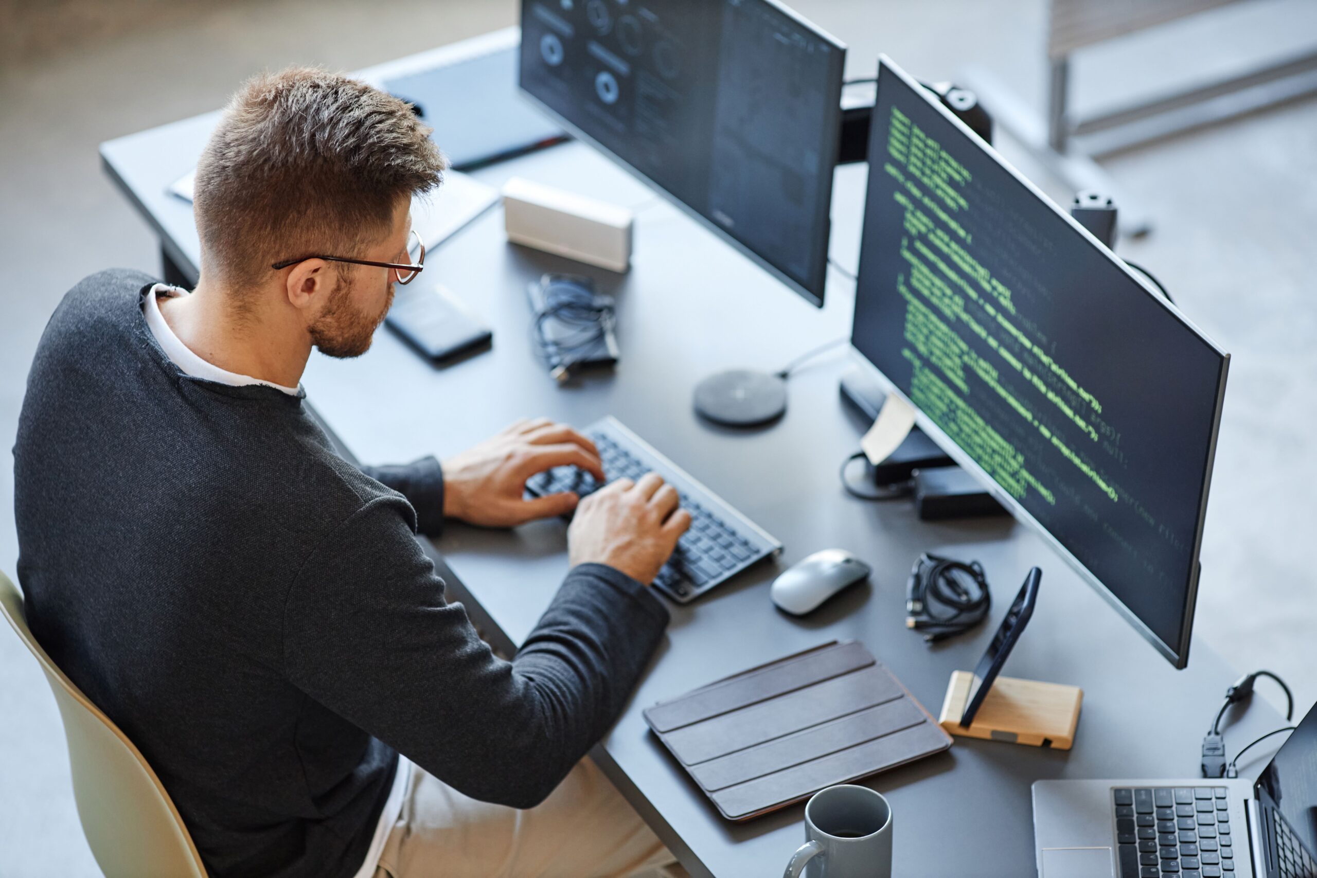 Eine Person sitzt an einem Computer und programmiert etwas 