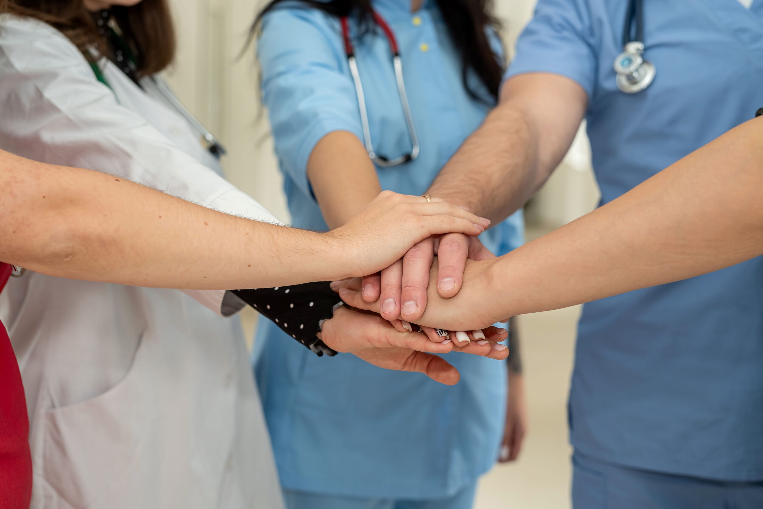 BEM Beauftragter unterstützt Team im Gesundheitswesen – mehrere Hände aufeinander symbolisieren Zusammenhalt und Vertrauen